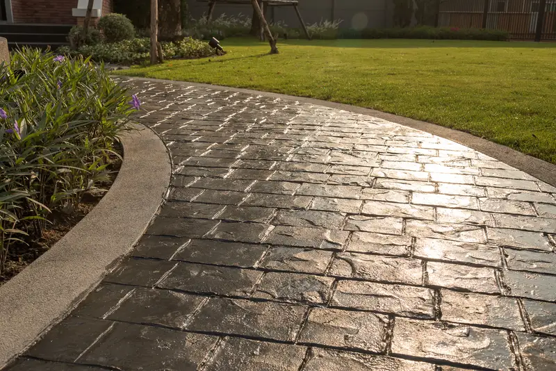 Stamped concrete walkway with a dark cobblestone pattern. Stamped concrete walkway with a dark cobblestone pattern.