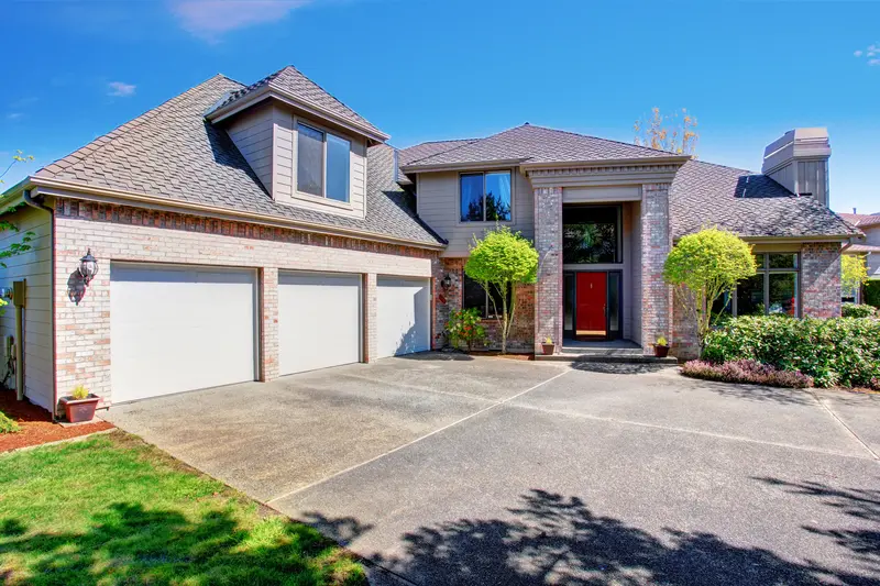 Large concrete driveway in front of a modern three-car garage. Large concrete driveway in front of a modern three-car garage.