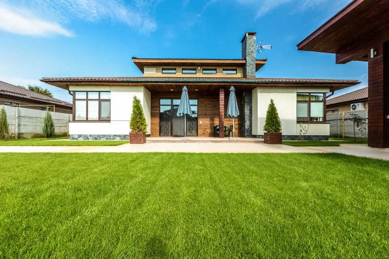 Modern home exterior with a clean concrete walkway and green lawn. Modern home exterior with a clean concrete walkway and green lawn.